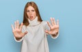 Young irish woman wearing casual winter sweater doing stop gesture with hands palms, angry and frustration expression