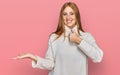 Young irish woman wearing casual winter sweater showing palm hand and doing ok gesture with thumbs up, smiling happy and cheerful Royalty Free Stock Photo