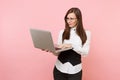 Young irritated dissatisfied business woman in glasses working in laptop pc computer on pastel pink background Royalty Free Stock Photo