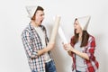 Young irritated woman, man in casual clothes holding wallpaper rolls and quarrelling. Couple isolated on white