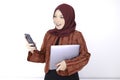 Young Islam woman is standing and smiling face when looking on the phone with holding laptop