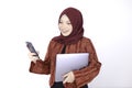 Young Islam woman is standing and smiling face when looking on the phone with holding laptop