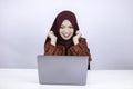 Young Islam woman wearing headscarf is shocked and excited with what she see on laptop on the table