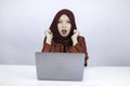 Young Islam woman wearing headscarf is shocked and excited with what she see on laptop on the table