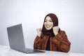 Young Islam woman wearing headscarf is shocked and excited with what she see on laptop on the table