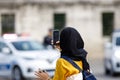 Young Islamic woman taking photos on phone, back view. Shooting video with cell phone camera, using smartphone to take pictures Royalty Free Stock Photo