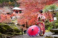 Young Japanese girl traveller in traditional kimino dress standing in Digoji temple with red pagoda and red maple leaf in autumn