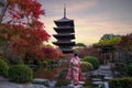 Young Japanese girl traveller in traditional kimino dress standing in Toji temple with wooden pagoda and red maple leaf in autumn Royalty Free Stock Photo