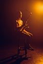 young jazzman looking at camera while sitting on stool