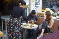 A young Jewish male at a cafe table in Jerusalem Israel using his mobile phone while his girlfriend waits patiently.