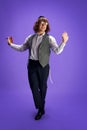 Young Jewish man with grogger dancing national dance holds grogger against purple studio background. Purim holiday. Ad Royalty Free Stock Photo