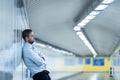 Young jobless business man suffering depression leaning on street underground wall alone looking desperate in Emotional pain