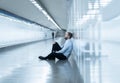 Young jobless business man suffering depression sitting on ground street underground leaning on wall alone looking desperate in Royalty Free Stock Photo