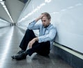 Young jobless business man suffering depression sitting on ground street underground leaning on wall alone looking desperate in Royalty Free Stock Photo