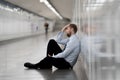 Young jobless business man suffering depression sitting on ground street underground leaning on wall alone looking desperate in Royalty Free Stock Photo