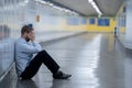 Young jobless business man suffering depression sitting on ground street underground leaning on wall alone looking desperate in Royalty Free Stock Photo