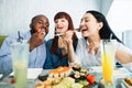 Young jolly multiracial friends eating sushi using chopsticks, looking positive and happy, sitting at asian restaurant