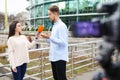 Young journalist interviewing man on street