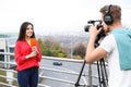 Young journalist and video operator working on street