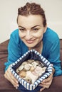 Young joyful brunette with various shells in sailor bag, beauty