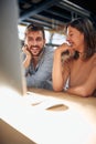Blurred faces of young man and woman colleagues talking in front of table with desktop computer, in clothing store Royalty Free Stock Photo