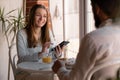 young joyful couple using cellphones and laughing while having breakfast in kitchen at home, bearded man and woman eat Royalty Free Stock Photo