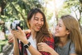 Young joyful friend asian women using camera to making photo during city tour, cheerful emotions.