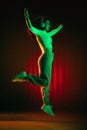 Young joyful girl jumping isolated on multicolored background in neon light.