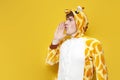 young joyful guy in funny children's giraffe pajamas announces and speaks on yellow background
