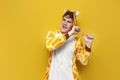 young joyful guy in funny children\'s giraffe pajamas dances on yellow background, man in animal cosplay clothes