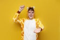 young joyful guy in funny children\'s giraffe pajamas dances on yellow background, man in animal cosplay clothes