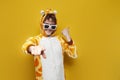 young joyful guy in funny children\'s giraffe pajamas and glasses invites you to party on yellow background