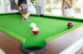 Young joyful man having a good time playing billiards or shooting for a snooker shot Royalty Free Stock Photo