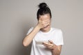 Young, joyful woman holds a smartphone in hand, sees something funny and laughs. She shyly closed eyes and part of face with her Royalty Free Stock Photo