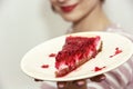 Young joyful woman with the piece of cheesecake with raspberries