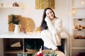 Young joyful woman stands in kitchen against background of Christmas decorations