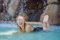 Young joyful woman under the water stream, pool, day spa, hot springs