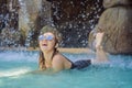 Young joyful woman under the water stream, pool, day spa, hot springs