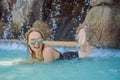 Young joyful woman under the water stream, pool, day spa, hot springs