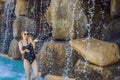 Young joyful woman under the water stream, pool, day spa, hot springs