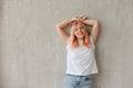 Young joyful woman in white t-shirt with dyed hair posing at wall with raised hands Royalty Free Stock Photo