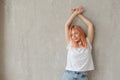 Young joyful woman in white t-shirt with dyed hair posing at wall with raised hands Royalty Free Stock Photo