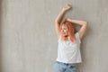 Young joyful woman in white t-shirt with dyed hair posing at wall with raised hands Royalty Free Stock Photo