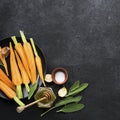 Young juicy carrots, sage, floral honey, garlic, salt ingredients for baking caramel spicy carrots. Top View.