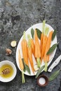 Young juicy carrots, sage, floral honey, garlic, salt ingredients for baking caramel spicy carrots. Top View