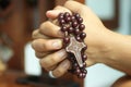 Young junior woman holding rosary in hand. Clasped hands praying holding a rosary with Jesus Christ Cross or Crucifix.