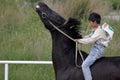 Young Asian boy is riding his pure breed black Kazakh horse in Kazakhstan steppe