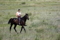 Young Asian man is riding his pure breed Kazakh horse in Kazakhstan steppe