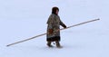 Young Khanty girl in national winter clothes holding a khorey long pole for driving a reindeer