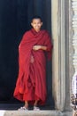 Young Khmer monk smiling in his red dress in Angkor, Cambodia